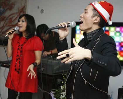 Tùng Dương đội mũ Noel đỏ, nhắm mắt và đưa tay khi hát mừng Giáng sinh