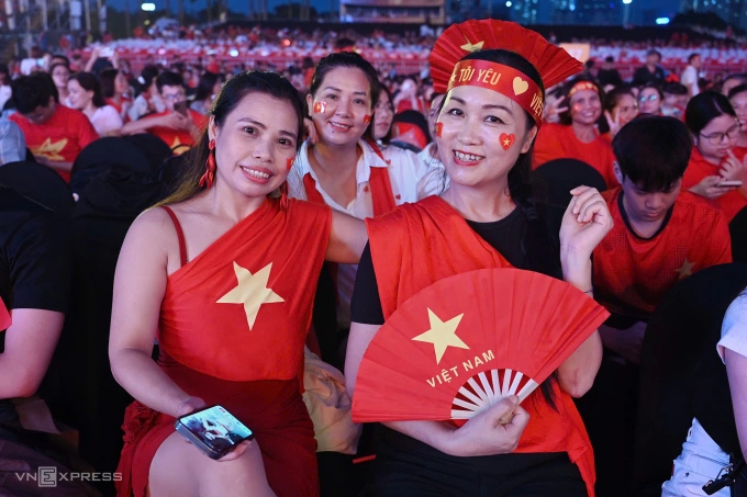 Khán giả mang nhiều khăn, phụ kiện màu đỏ và vàng. Mỗi người đều được ban tổ chức phát áo mưa, nước.