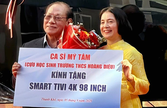 Bố Mỹ Tâm (trái) thay con gái trao quà cho đại diện trường THCS Hoàng Diệu. Ảnh: Nhân vật cung cấp