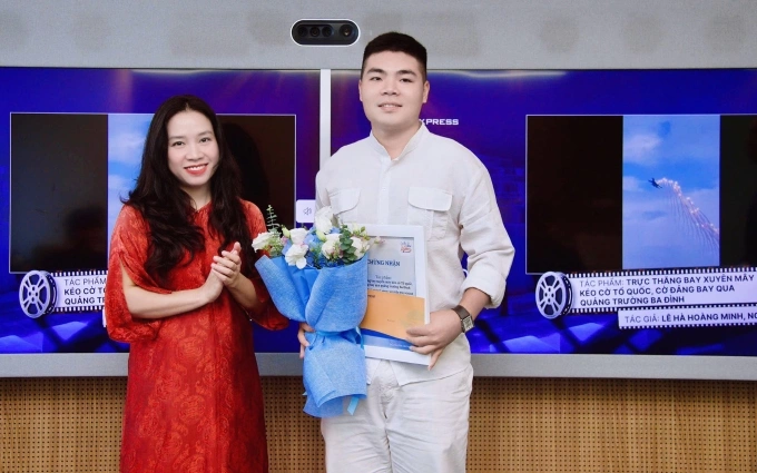 Bà Nguyễn Thu Hương - Phó tổng Biên tập Báo VnExpress - trao giải nhì cho anh Lê Hà Hoàng Minh, đồng tác giả tác phẩm Trực thăng bay xuyên mây kéo cờ Tổ quốc, cờ Đảng bay qua quảng trường Ba Đình. Ảnh: Duy Anh