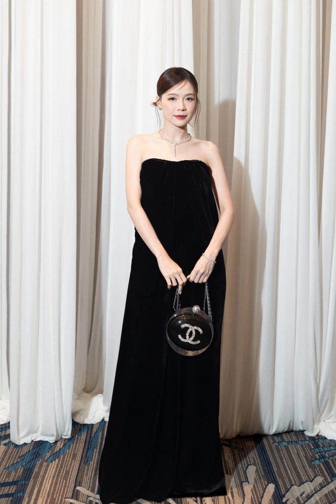 Sam phối đầm hở vai, xách túi hiệu dự tiệc.